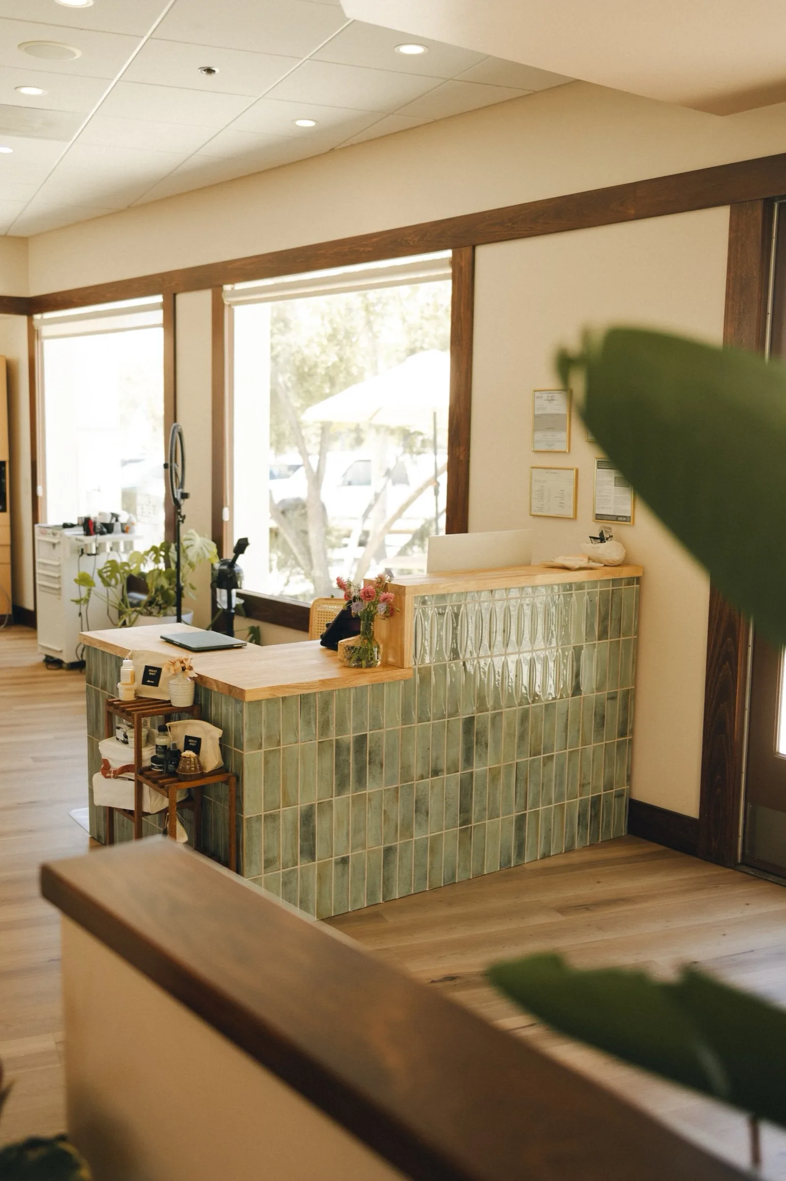 A green tiled reception counter with a wood top in a sunlit interior