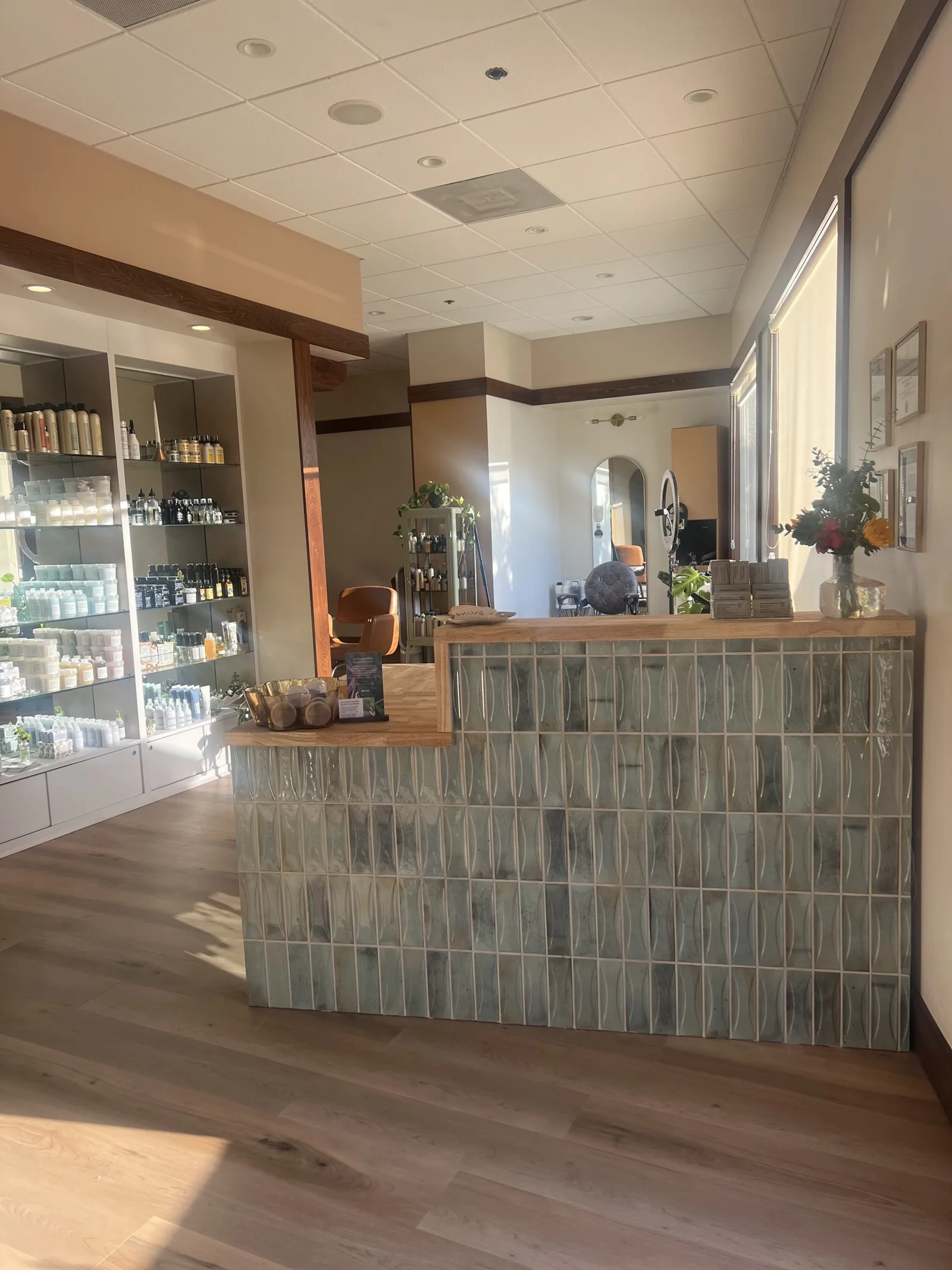A tiled service counter with a wood top in a retail shop with product shelving behind